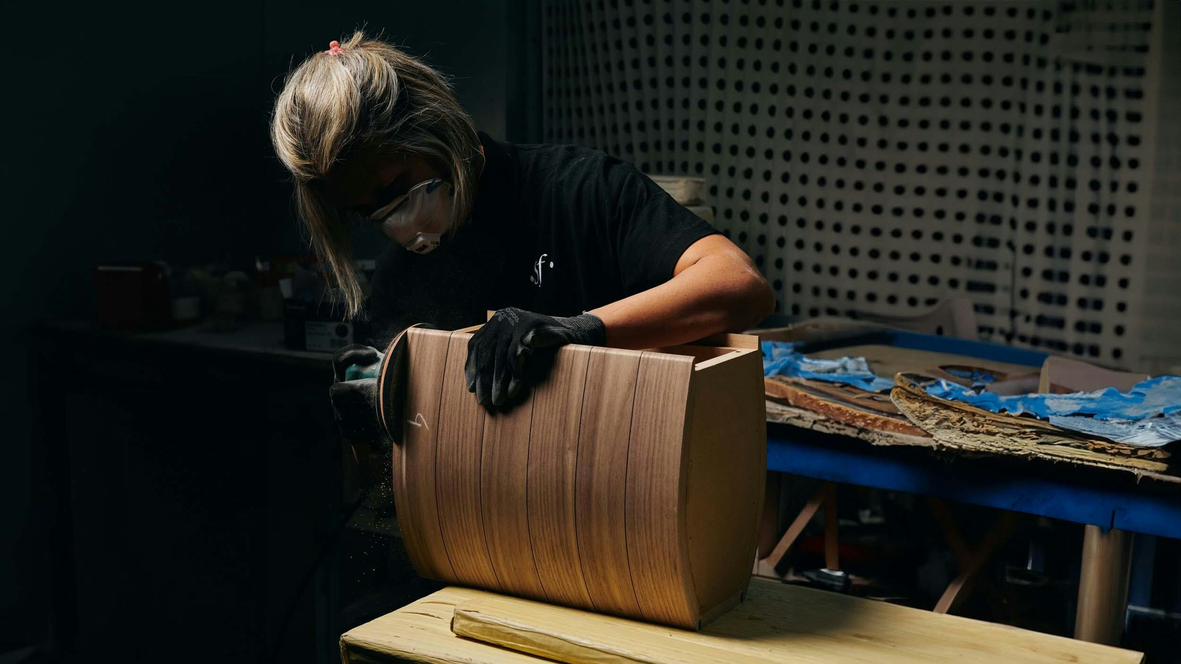 Sonus faber Italian artisan hand-sanding wood for Guarneri G5 bookshelf speaker, showcasing meticulous craftsmanship.