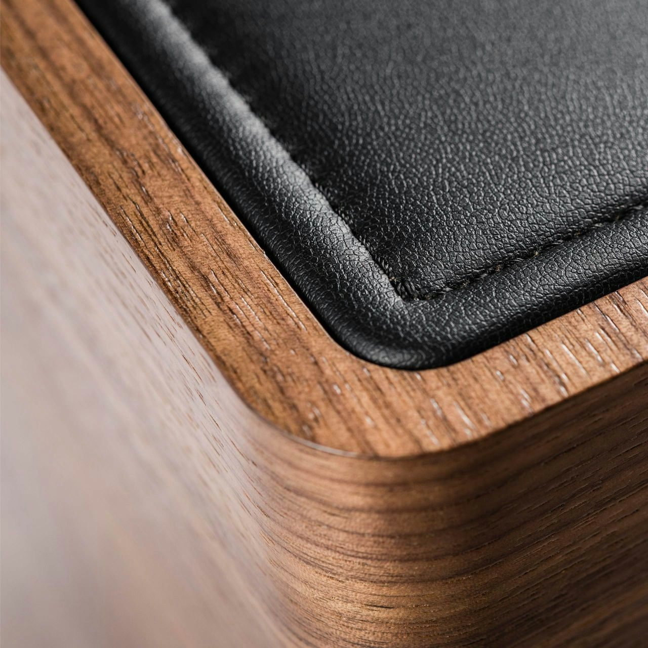 Detailed view of the Sonus faber Gravis I subwoofer in walnut wood and black leather top, highlighting the natural materials.