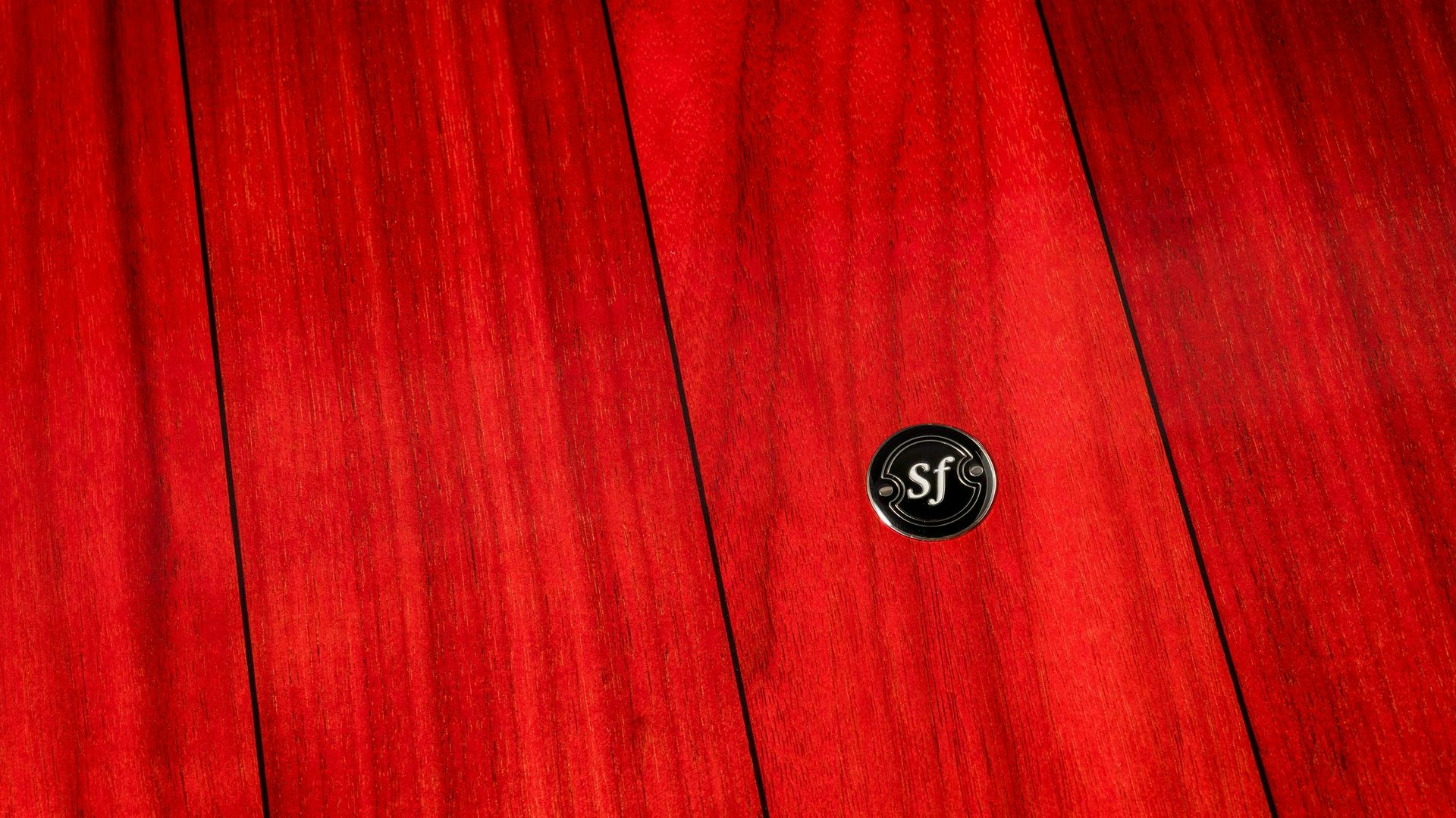 Sonus faber Gravis subwoofer, spotlighting the striking red wood finish and featuring the iconic 'sf' logo for added distinction.