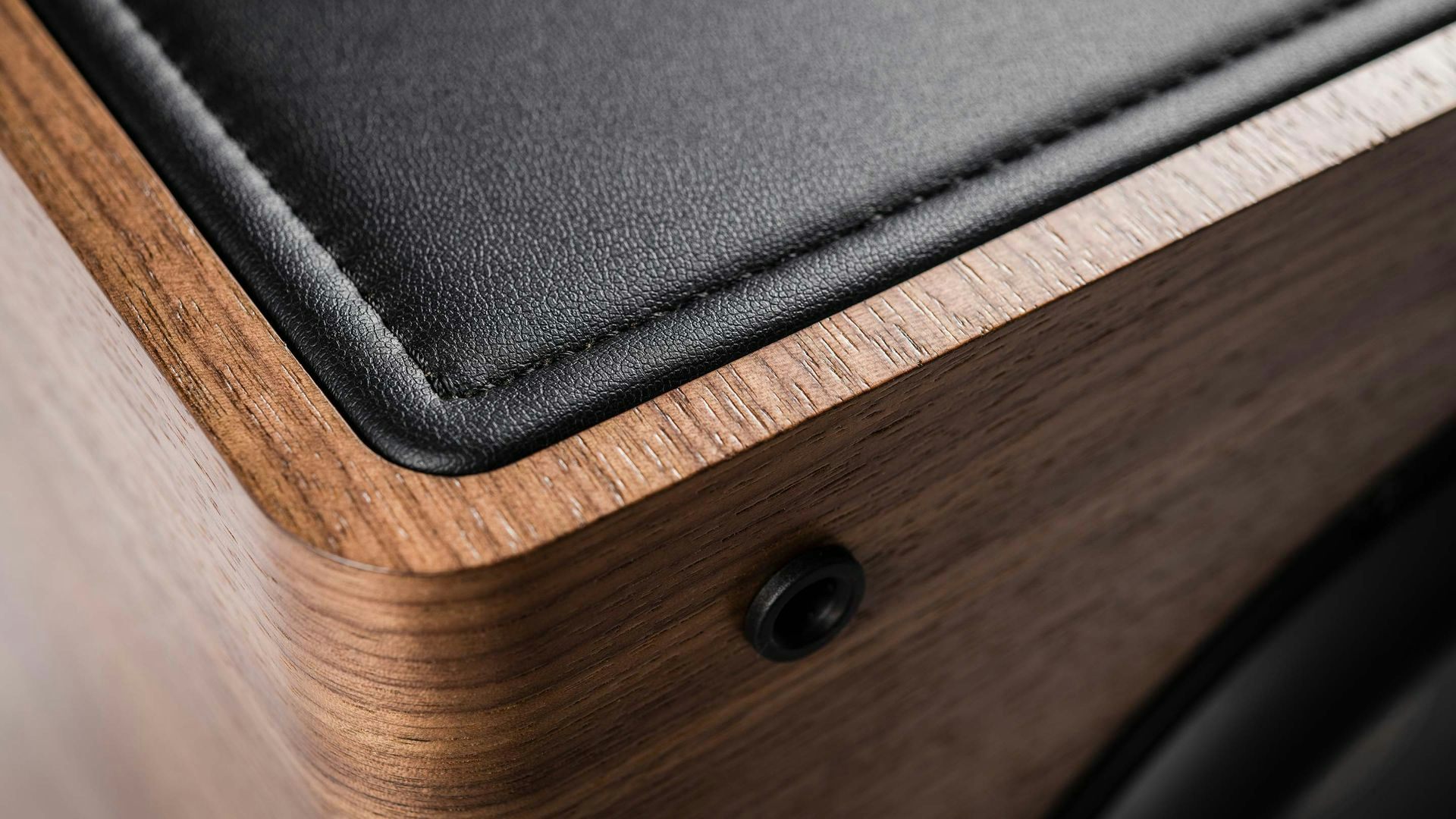 Close-up of the walnut wood and black leather top on a Sonus faber Gravis II subwoofer, showcasing natural materials.