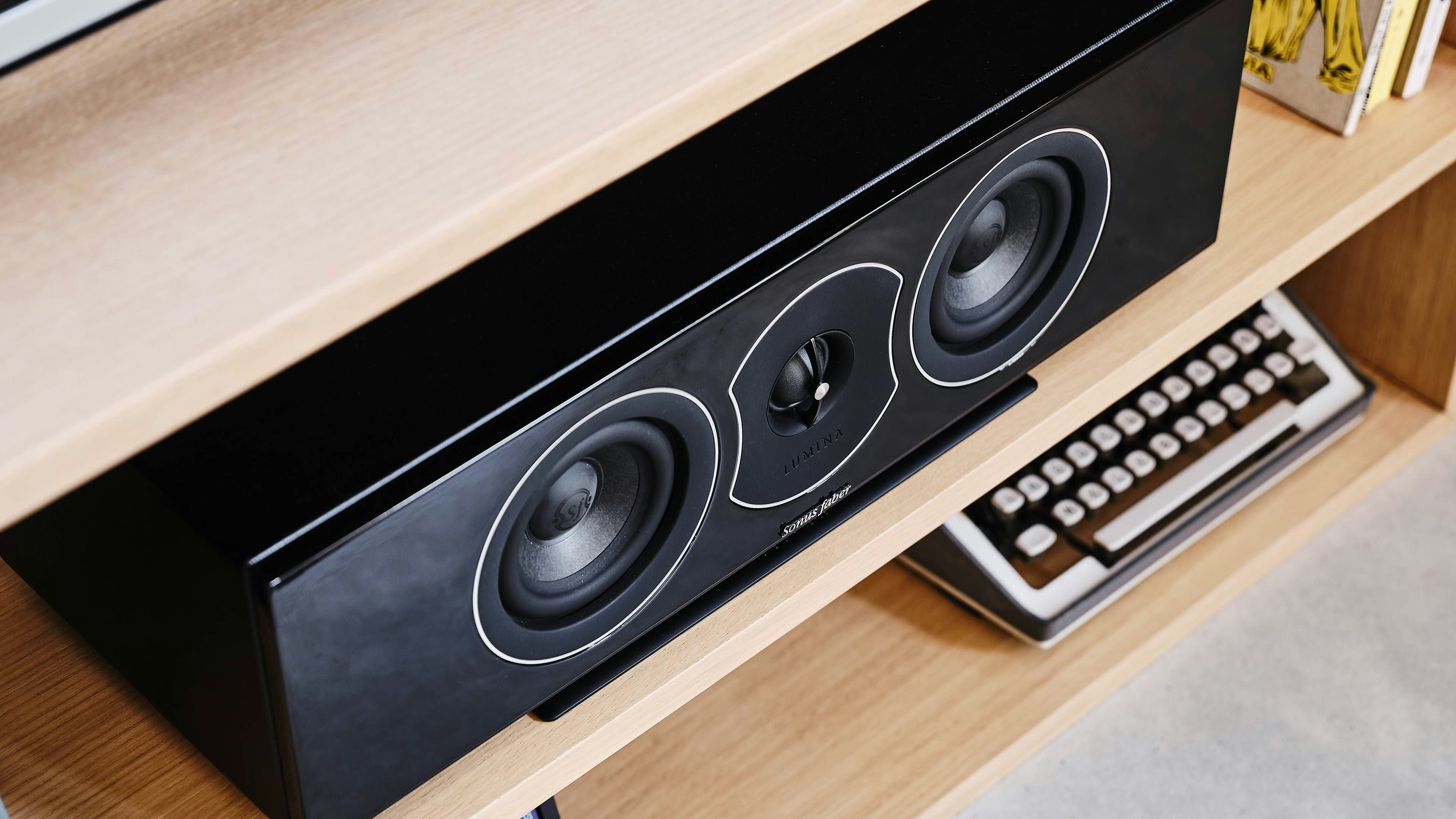 Sonus faber Lumina CI center speaker in stylish piano black lacquer, elevating a home cinema experience on a sleek TV stand.